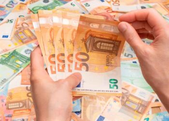 Manos contando billetes de 50 € ilustran el pago único de 37.800 € del SEPE para emprender