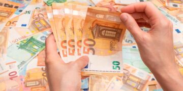 Manos contando billetes de 50 € ilustran el pago único de 37.800 € del SEPE para emprender