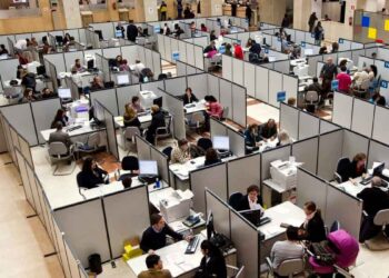 Funcionarios atendiendo a ciudadanos en una oficina pública; la nueva ley plantea suspender empleo y sueldo por retrasos reiterados