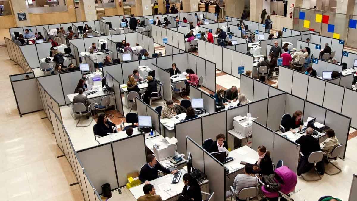 Funcionarios atendiendo a ciudadanos en una oficina pública; la nueva ley plantea suspender empleo y sueldo por retrasos reiterados