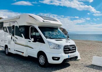 Autocaravana blanca aparcada junto al mar en España, lista para ser domicilio y padrón