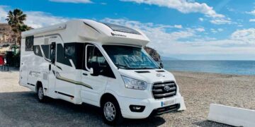 Autocaravana blanca aparcada junto al mar en España, lista para ser domicilio y padrón