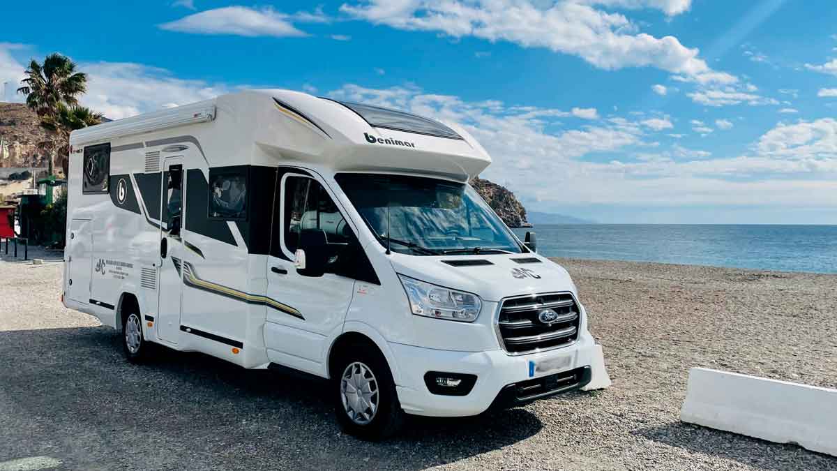 Autocaravana blanca aparcada junto al mar en España, lista para ser domicilio y padrón
