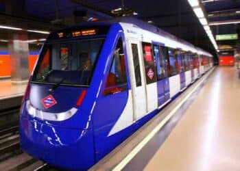 Niños madrileños enseñan su tarjeta roja Abono 7-14 en el andén del Metro, símbolo del transporte gratis 2025.