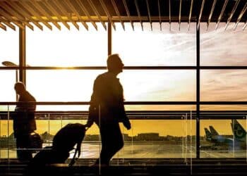 Desempleado con maleta en un aeropuerto al amanecer; viajar sin avisar al SEPE puede hacer perder la prestación por desempleo