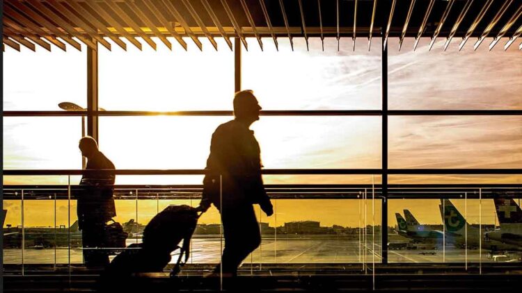 Desempleado con maleta en un aeropuerto al amanecer; viajar sin avisar al SEPE puede hacer perder la prestación por desempleo