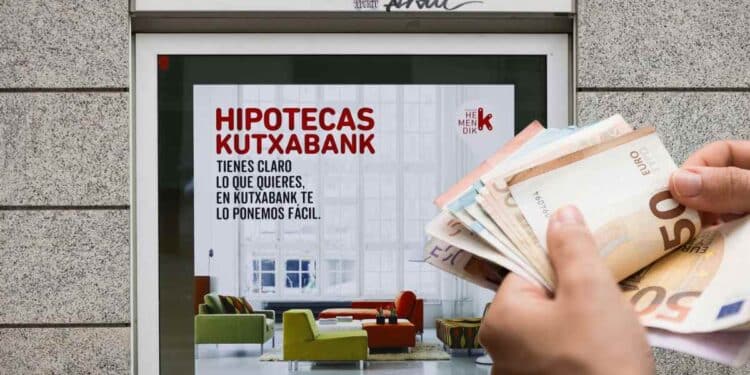 Ayudas para pagar la hipoteca 2025: anuncio de hipotecas Kutxabank y mano con billetes de euro.