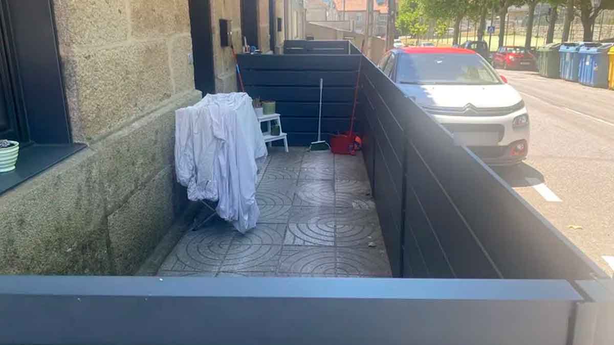 Acera pública en Navia (Vigo) cerrada con paneles para usarla como terraza particular; el Ayuntamiento exige derribarla
