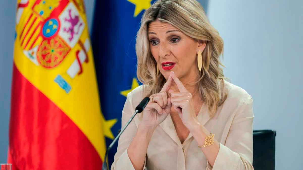 La ministra de Trabajo gesticula en rueda de prensa sobre el salario mínimo interprofesional, con banderas de España y la Unión Europea al fondo