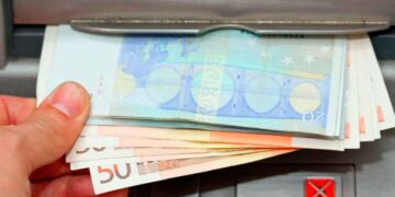 Mano retirando billetes de 20 y 50 € en cajero, símbolo del cobro del paro de junio 2025 adelantado por varios bancos
