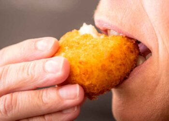 Primer plano de una persona mordiendo una croqueta dorada, eje del despido declarado improcedente por el TSJ de Castilla-La Mancha
