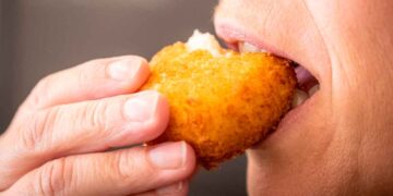Primer plano de una persona mordiendo una croqueta dorada, eje del despido declarado improcedente por el TSJ de Castilla-La Mancha