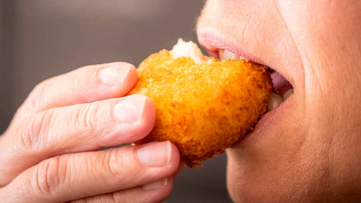 Primer plano de una persona mordiendo una croqueta dorada, eje del despido declarado improcedente por el TSJ de Castilla-La Mancha
