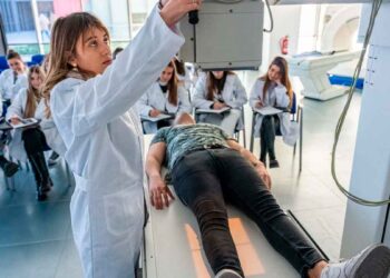Profesora de FP Sanitaria ajusta equipo de rayos X mientras el alumnado observa la práctica clínica en Madrid, curso 2025-26