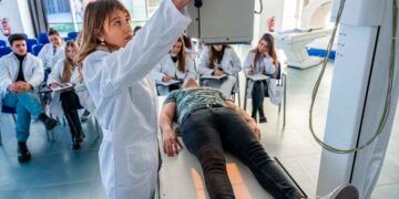 Profesora de FP Sanitaria ajusta equipo de rayos X mientras el alumnado observa la práctica clínica en Madrid, curso 2025-26