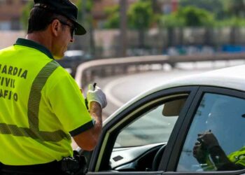 Agente de la Guardia Civil de Tráfico sancionando a un pasajero en un control, posible multa de hasta 500 € por infracción vial