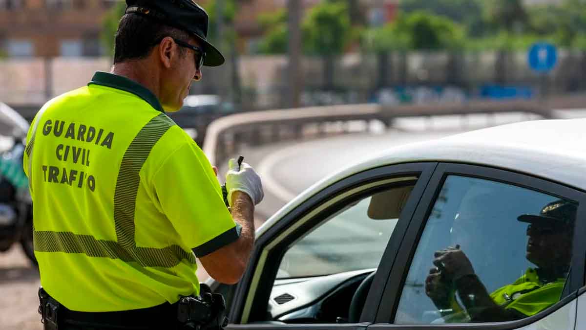 Agente de la Guardia Civil de Tráfico sancionando a un pasajero en un control, posible multa de hasta 500 € por infracción vial