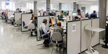 Personas siendo atendidas en cubículos numerados de la Agencia Tributaria para presentar la declaración presencial de la Renta 2024/25