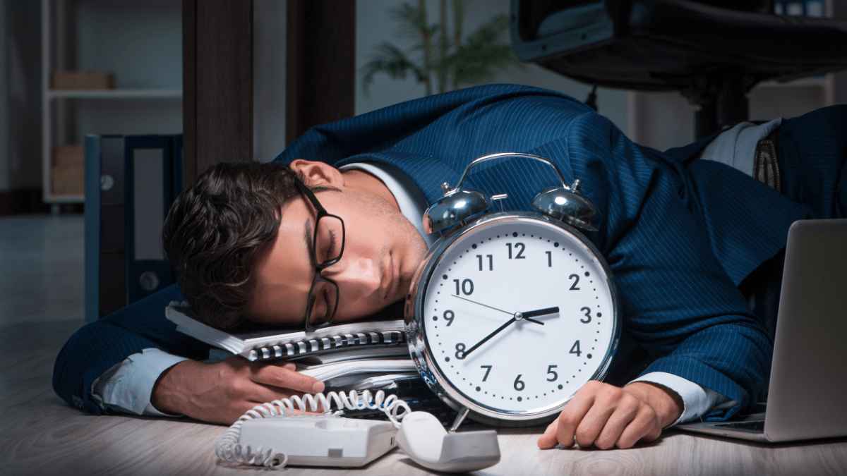 Empleado agotado dormido junto a un gran reloj, símbolo de las horas extra obligatorias según el Estatuto de los Trabajadores.