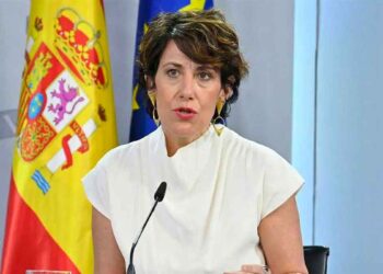 Elma Saiz en rueda de prensa anuncia la jubilación anticipada sin recortes desde los 52 años, con bandera nacional al fondo