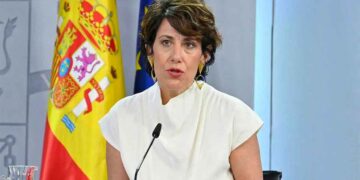 Elma Saiz en rueda de prensa anuncia la jubilación anticipada sin recortes desde los 52 años, con bandera nacional al fondo