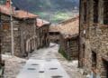Calle empedrada en La Hiruela, pueblo medieval de la Sierra Norte de Madrid, con casas de piedra y tejados rojizos.