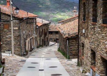 Calle empedrada en La Hiruela, pueblo medieval de la Sierra Norte de Madrid, con casas de piedra y tejados rojizos.