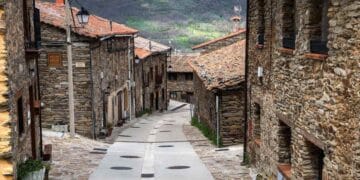 Calle empedrada en La Hiruela, pueblo medieval de la Sierra Norte de Madrid, con casas de piedra y tejados rojizos.
