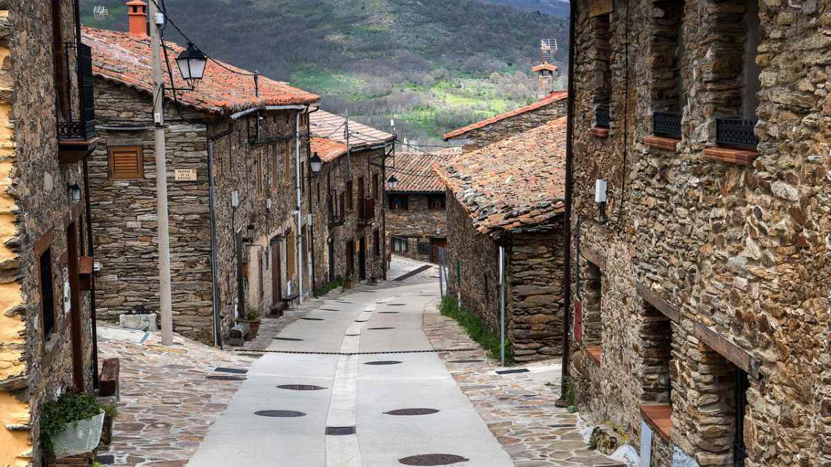 Calle empedrada en La Hiruela, pueblo medieval de la Sierra Norte de Madrid, con casas de piedra y tejados rojizos.