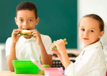 Dos escolares comen bocadillos en clase gracias al programa de desayunos gratuitos de Madrid 2025-2026