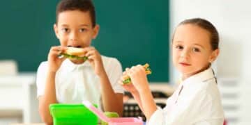 Dos escolares comen bocadillos en clase gracias al programa de desayunos gratuitos de Madrid 2025-2026