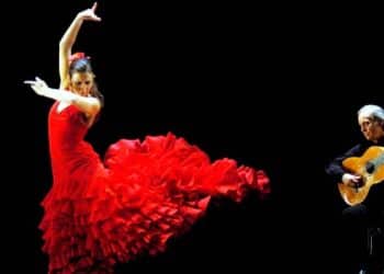 Bailaora flamenca con vestido rojo y guitarrista en escena, símbolo del decreto de Madrid que lleva el flamenco a los estudios superiores