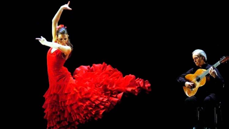 Bailaora flamenca con vestido rojo y guitarrista en escena, símbolo del decreto de Madrid que lleva el flamenco a los estudios superiores