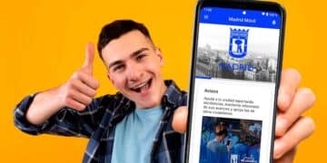 Joven sonriente muestra la app madrid móvil en su smartphone para gestionar trámites del ayuntamiento