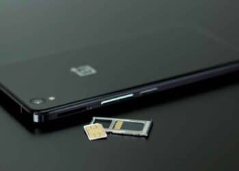 Teléfono móvil negro con bandeja y tarjeta SIM extraídas, ilustrando la transición a la nueva eSIM integrada