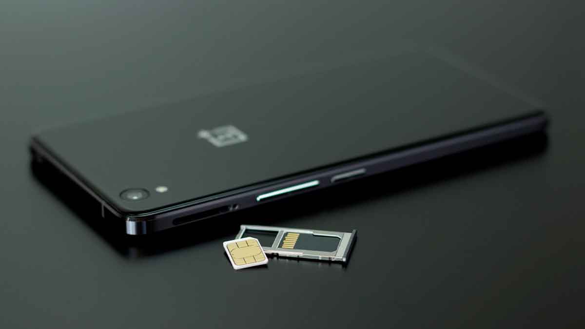 Teléfono móvil negro con bandeja y tarjeta SIM extraídas, ilustrando la transición a la nueva eSIM integrada