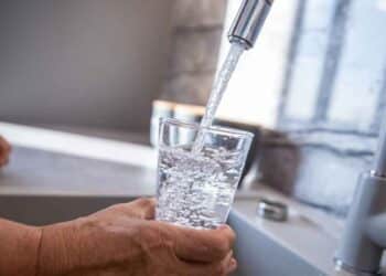 Vaso llenándose con agua del grifo en cocina – OCU revela la ciudad española con la mejor calidad
