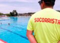 Socorrista con camiseta amarilla supervisa una piscina al aire libre en Madrid, cerrada por falta de personal durante la ola de calor