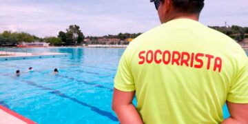 Socorrista con camiseta amarilla supervisa una piscina al aire libre en Madrid, cerrada por falta de personal durante la ola de calor