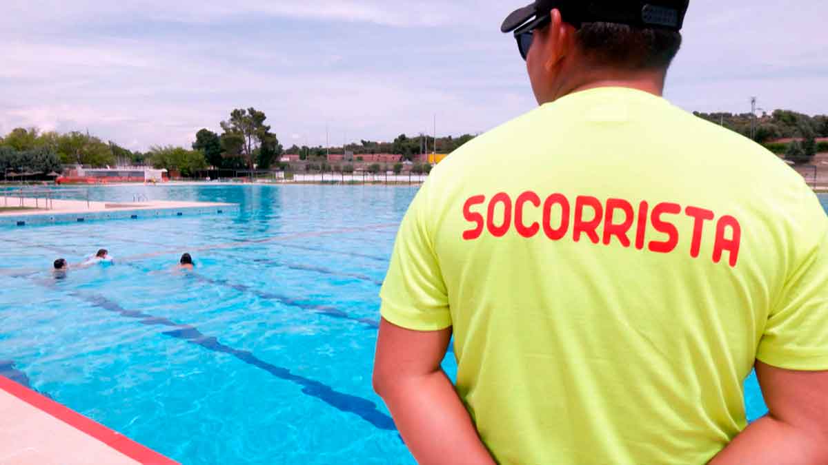 Socorrista con camiseta amarilla supervisa una piscina al aire libre en Madrid, cerrada por falta de personal durante la ola de calor