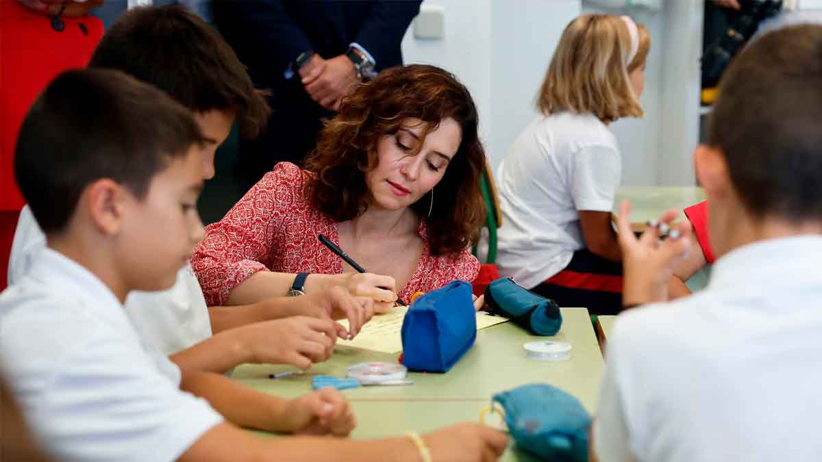 Ayuso junto a alumnos en un aula durante la presentación del programa “Patios abiertos” que ampliará el horario de los colegios madrileños
