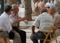 Grupo de jubilados sentados y conversando en una plaza arbolada de España