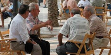 Grupo de jubilados sentados y conversando en una plaza arbolada de España