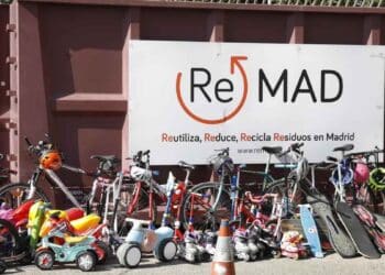 Bicicletas, patinetes y monopatines ante el cartel de ReMAD en un punto limpio de Madrid listos para su reutilización.