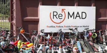 Bicicletas, patinetes y monopatines ante el cartel de ReMAD en un punto limpio de Madrid listos para su reutilización.