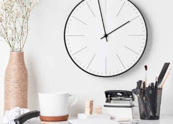 Reloj de pared y taza de café en escritorio que simbolizan los 15 minutos de cortesía y el descanso laboral avalados por el Supremo