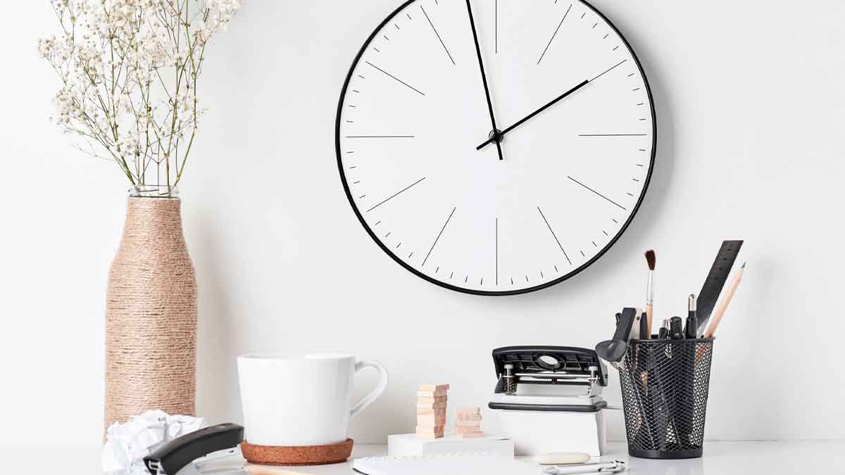 Reloj de pared y taza de café en escritorio que simbolizan los 15 minutos de cortesía y el descanso laboral avalados por el Supremo