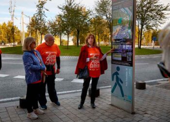 Grupo de participantes con camisetas “Gente que Camina” consultando el panel informativo de una ruta WAP en Madrid