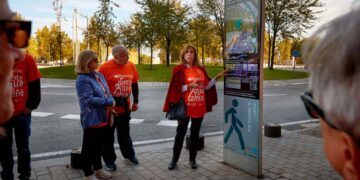 Grupo de participantes con camisetas “Gente que Camina” consultando el panel informativo de una ruta WAP en Madrid