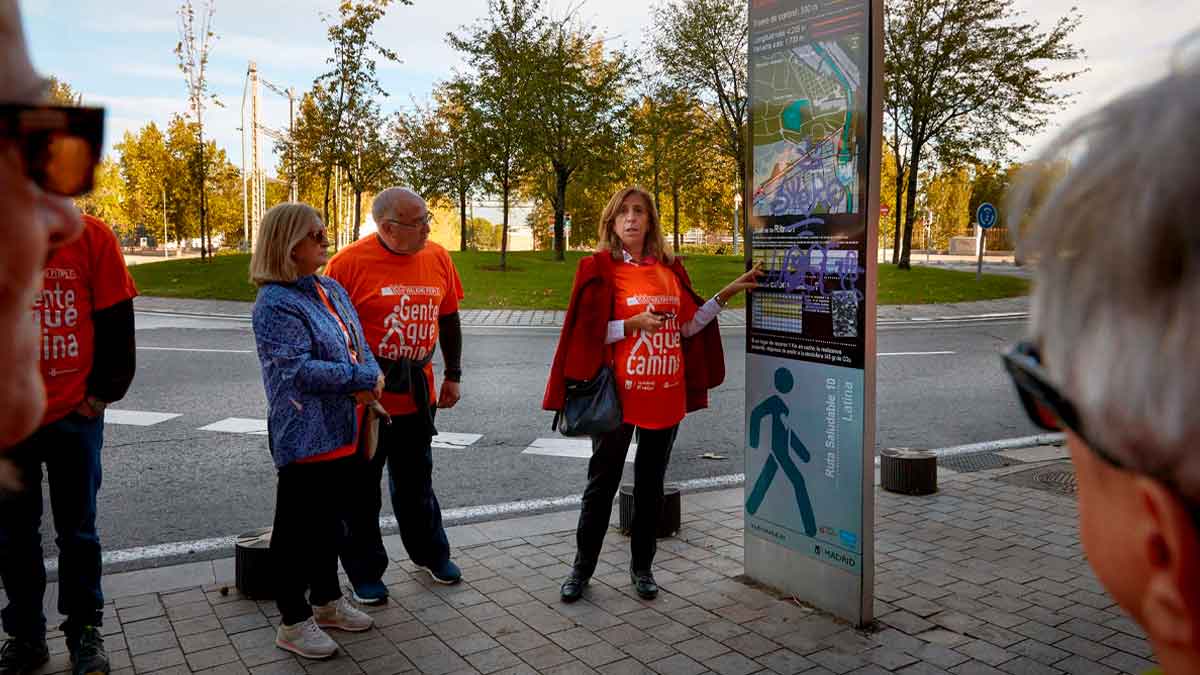 Grupo de participantes con camisetas “Gente que Camina” consultando el panel informativo de una ruta WAP en Madrid